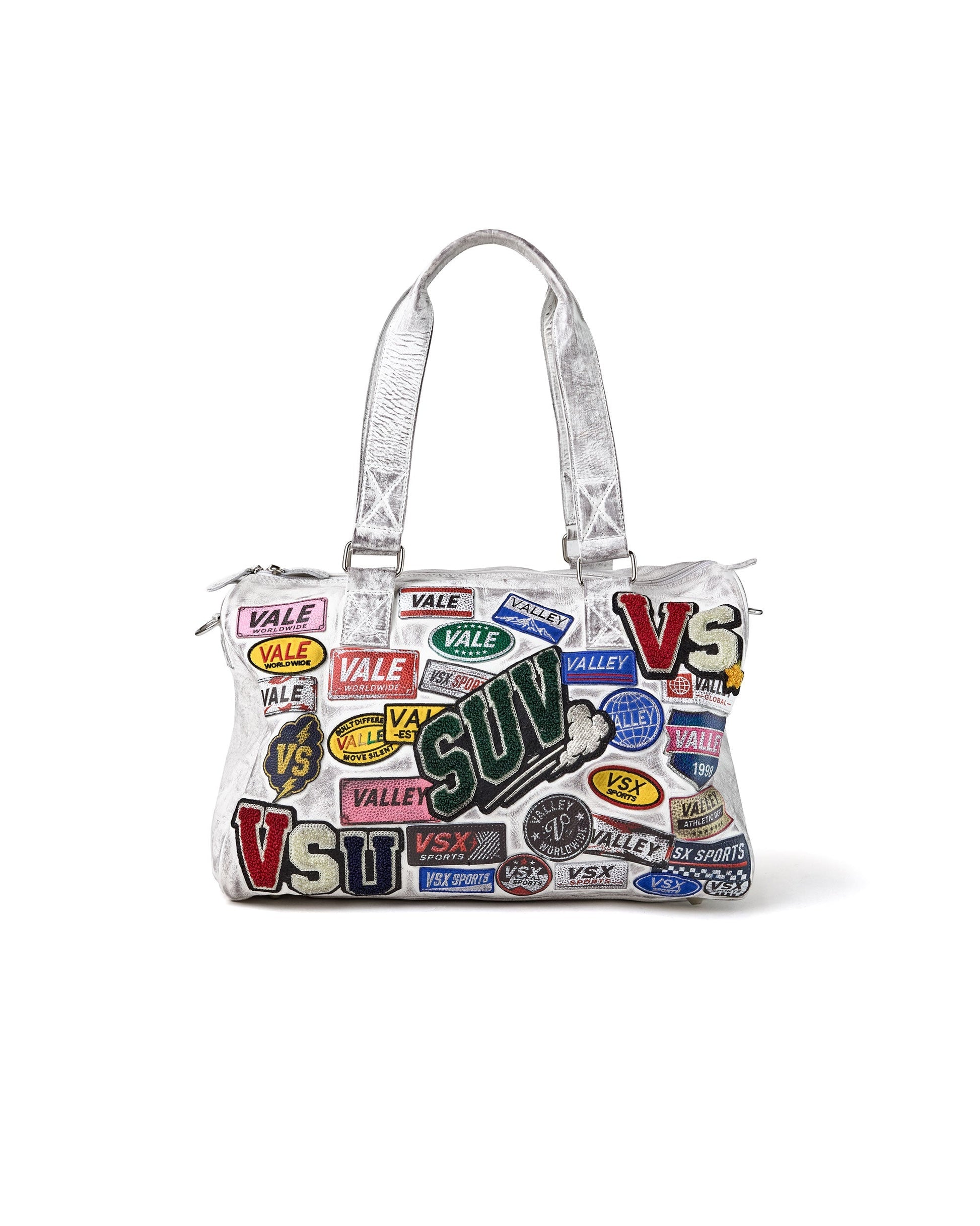 A white handbag covered in colorful 'VALE', 'VSU' and 'SUV' patches, featuring white shoulder straps, set against a plain white background.